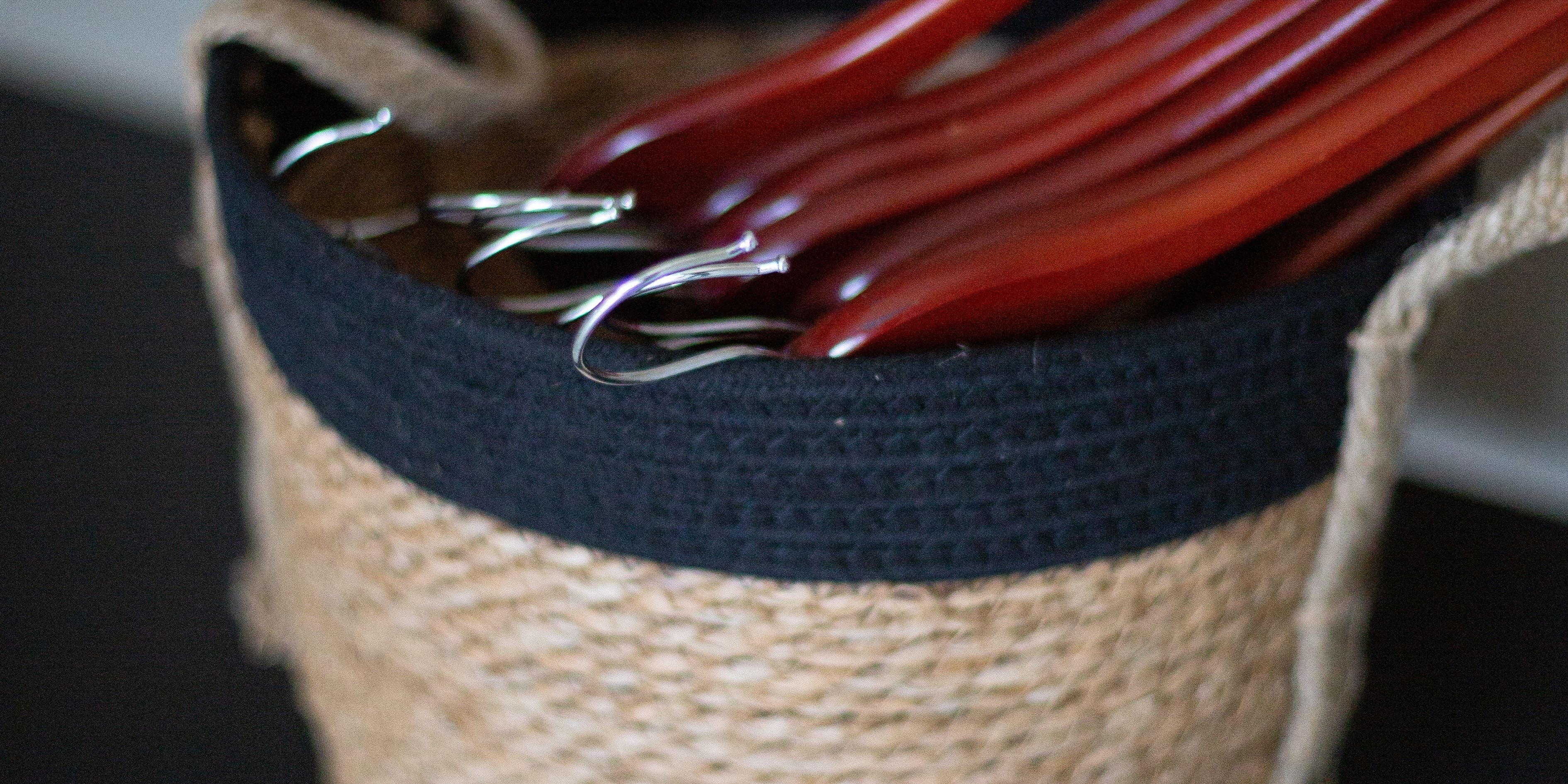 Natural hemp basket with black cotton top storing wooden hangers.